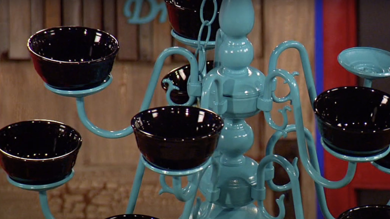 A bird feeder made from a chandelier with bowls for bird seed in place of bulbs.