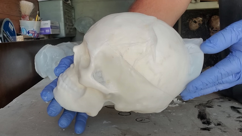 Gloved hands holding a DIY skull made from a plastic milk jug