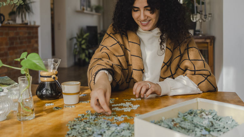 A person scatters jigsaw pieces on a table