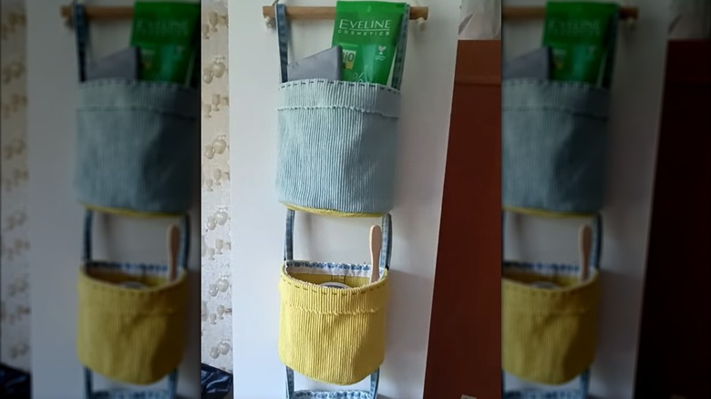 Three corduroy baskets hang in a row from a dowel on a wall.