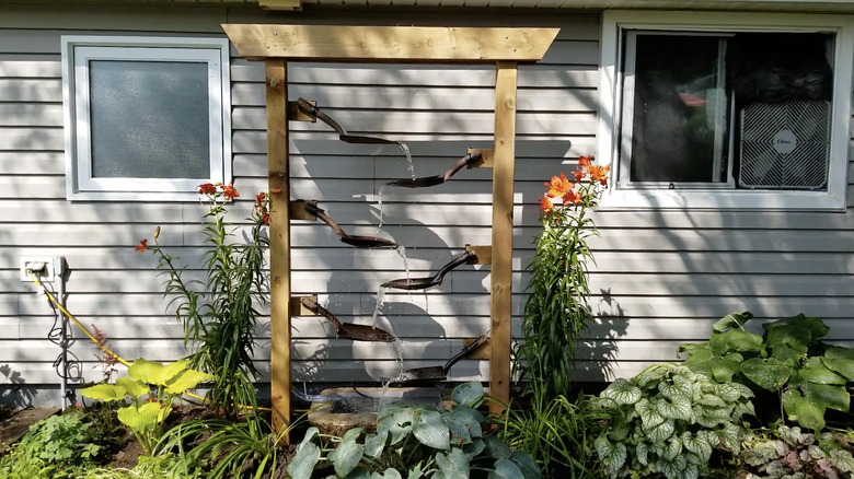 Water zig-zags down a fountain made from six shovel blades suspended by a wooden frame