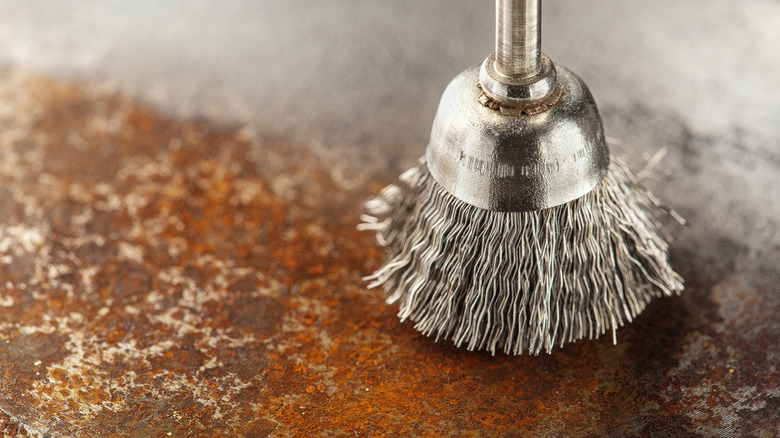 A close-up image of a steel brush drill attachment removing rust from a metal surface