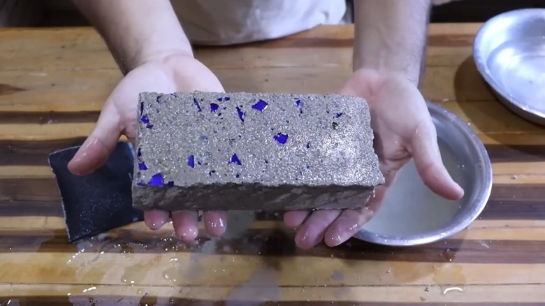 Person holding DIY brick paver made with glass shards for decoration