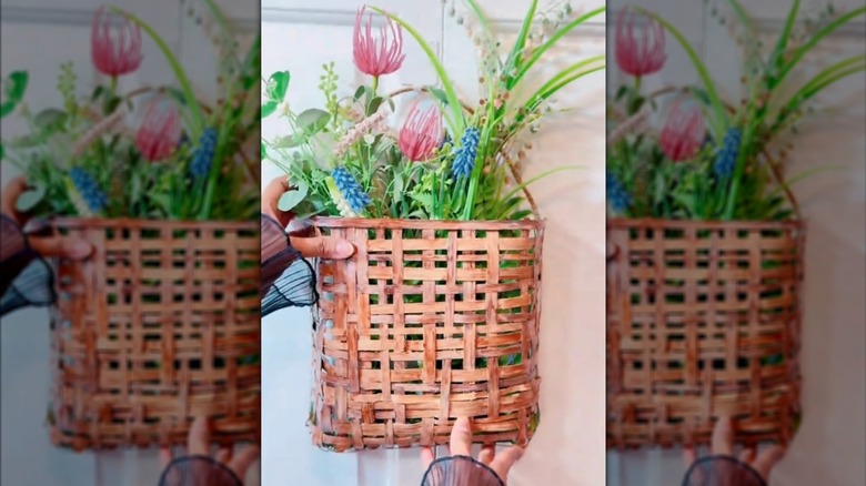Hanging woven basket decor filled with flowers and greenery.