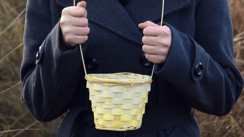 Person holding a small yellow basket.