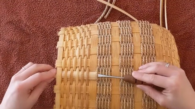 Person deconstructing a woven basket.