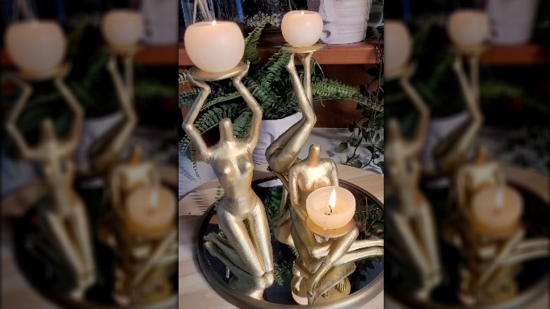 Gold-painted dolls holding candles on a mirrored centerpiece