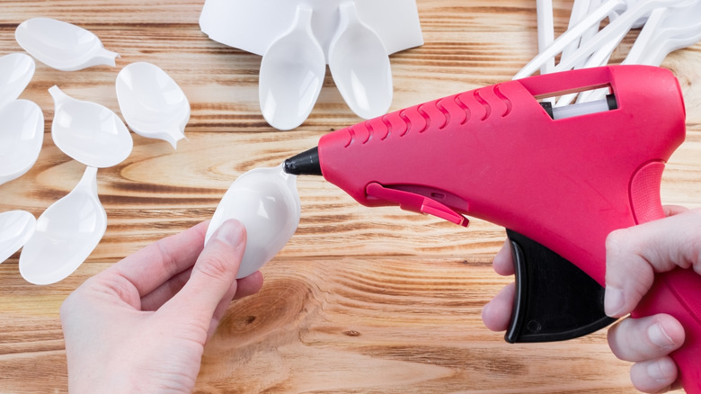 Person adding hot glue plastic spoon heads