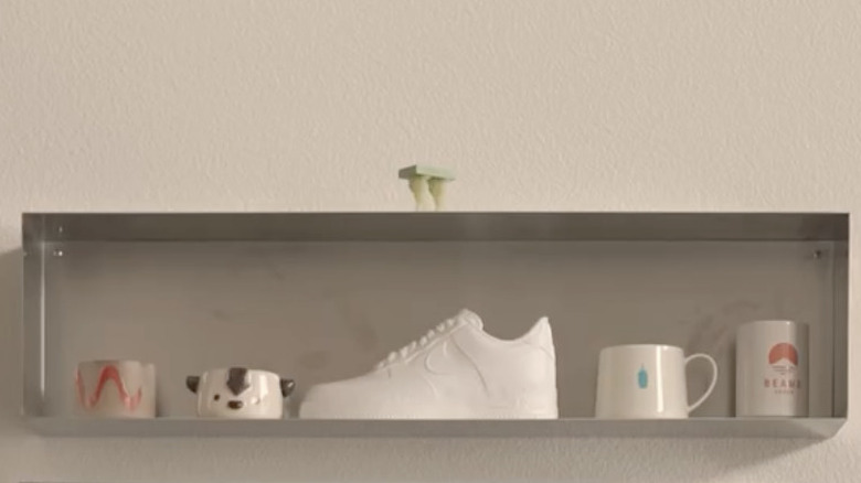 Metal planter mounted on a wall and lined with decor items such as mugs