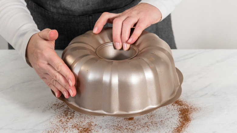 A woman holding a bundt pan upside down