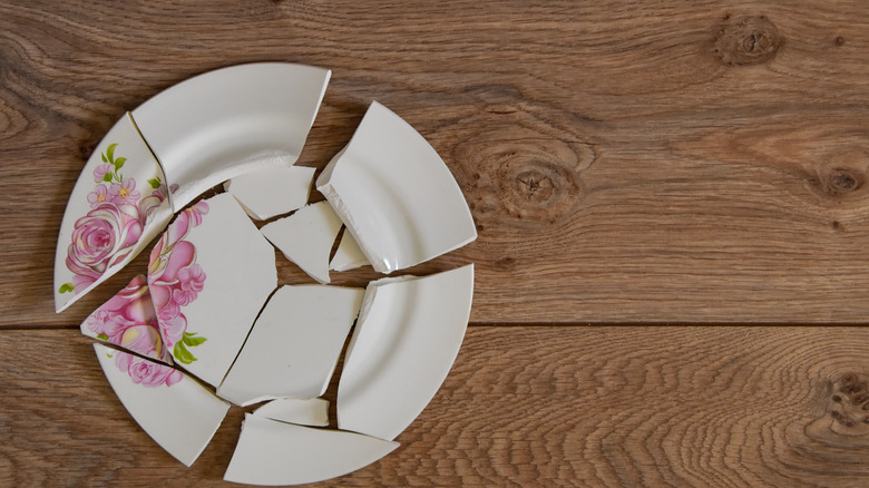 Shattered white plate with roses on a wood floor or table
