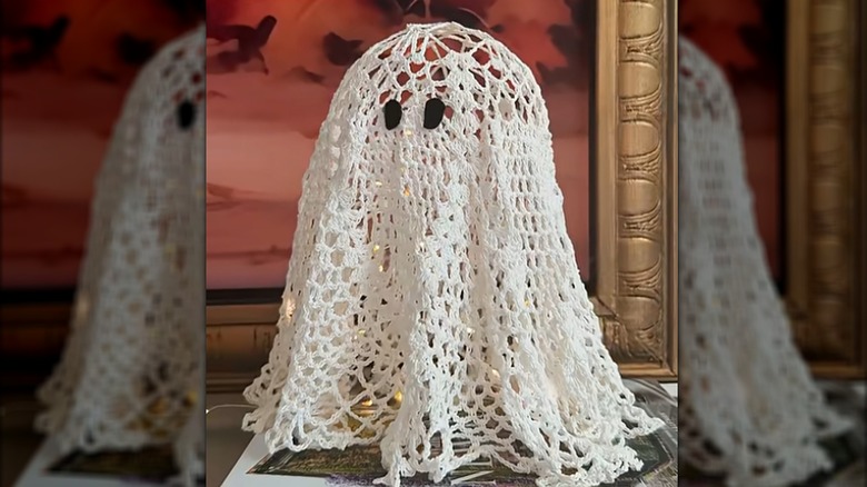 A ghost decoration made from a doily glows with LED lighting.