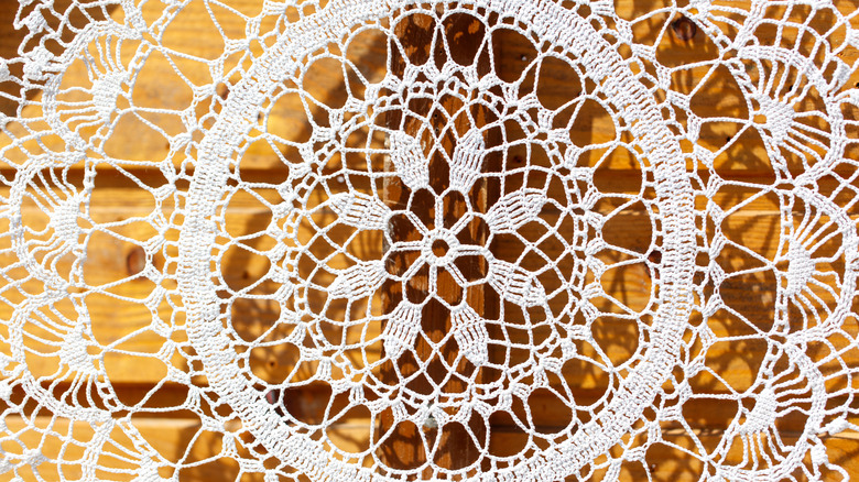 Light passes through a white doily set against a wooden background.