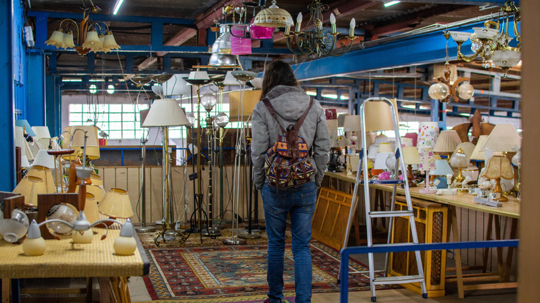 A woman shops for second hand lighting at a thrift store.