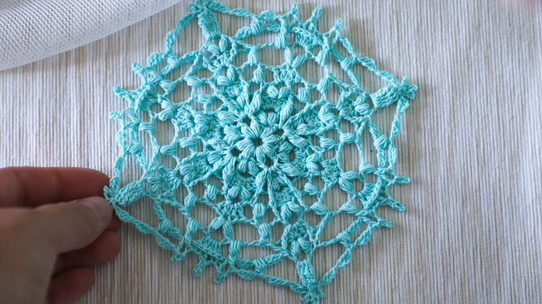 Person with fingers on a thrifted turquoise doily