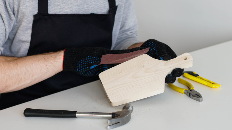 Person sanding the edge of a cheese board