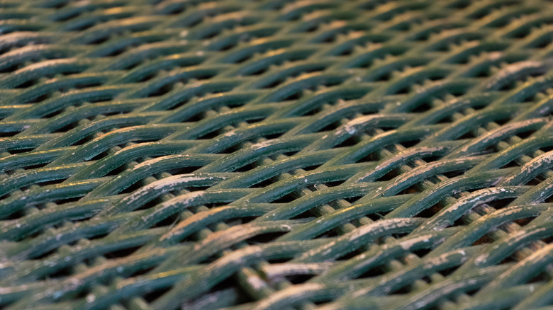 A close up of worn out green wicker furniture.
