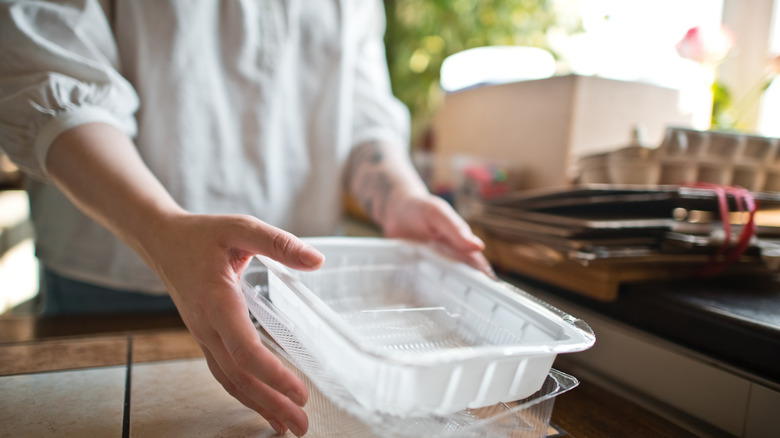 Person holding used plastic containers in kitchen