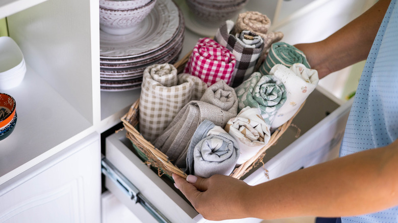 Vintage dish towels in a basket being taken out of a drawer