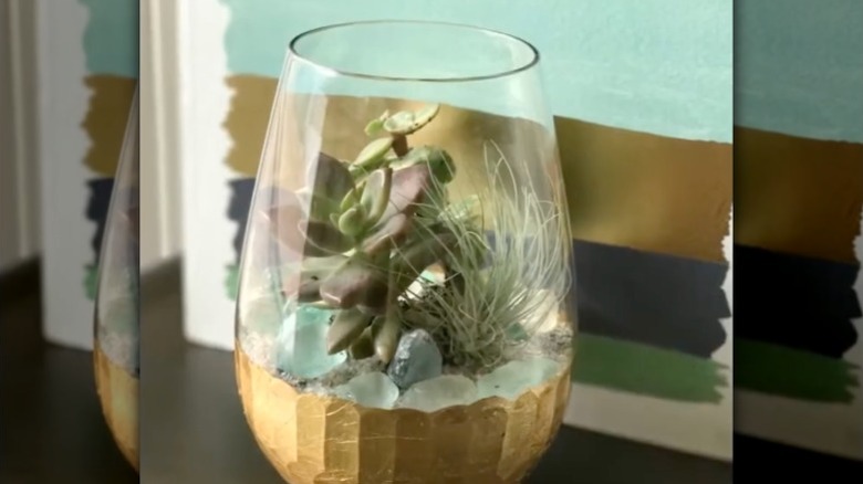 Succulents planted inside a stemless wine glass with gold detailing.