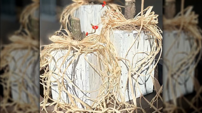 Rustic wood block pumpkins painted white and adorned with raffia