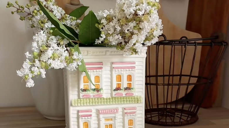 house-shaped cookie jar holding flowers