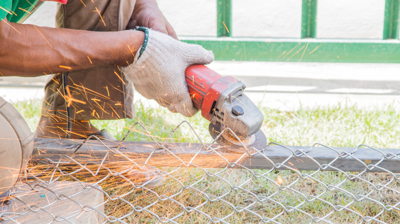 Person cutting chain link fencing outdoors