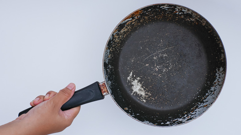 Person holding worn frying pan.