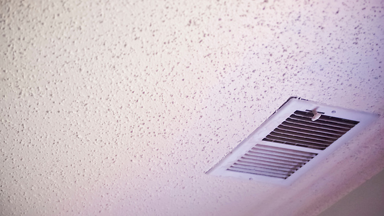 A white popcorn ceiling and a ceiling vent.