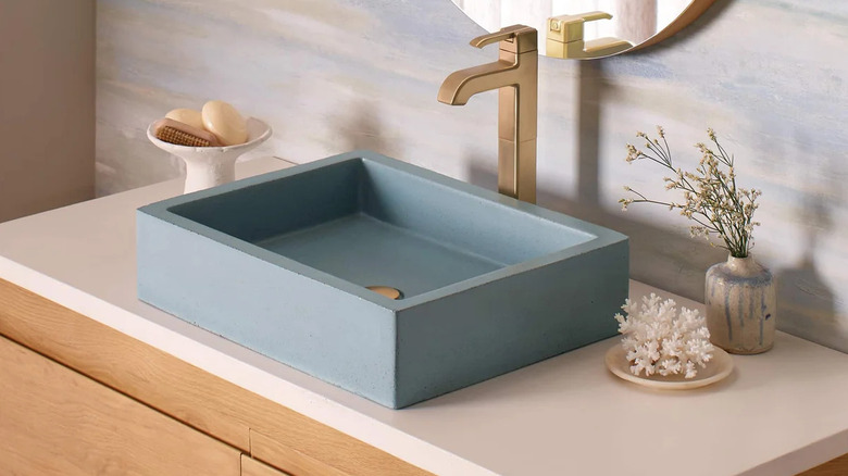 A pale blue bathroom sink on a while and natural wood vanity