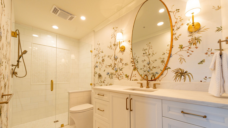 A white bathroom with floral wallpaper