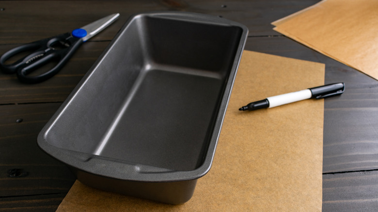 Loaf pan on table with parchment paper, marker, and scissors