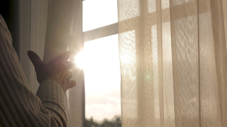 Person opening window to sun