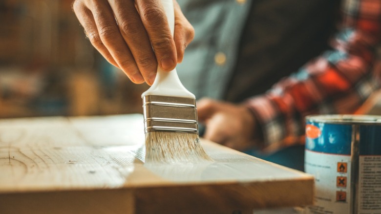 Person adding varnish on a table top