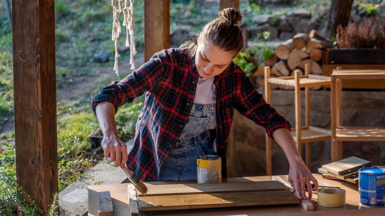 Woman outside staining wooden slats