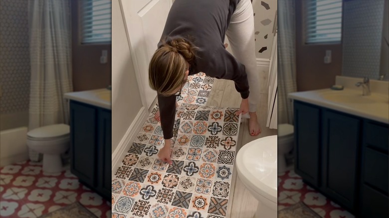 Woman bending over and applying contact paper to bathroom floors