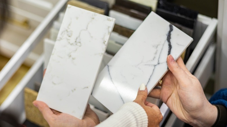 Hands holding white marble tile samples in showroom