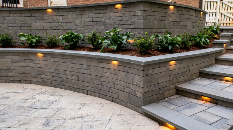 A retaining wall given a masonry look using stone veneers