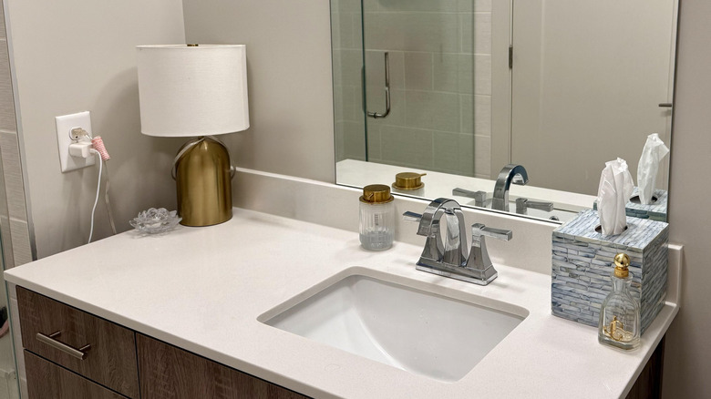 A modern bathroom with a gold lamp.