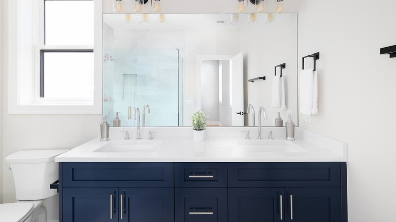 A double sink vanity with navy blue cabinets.