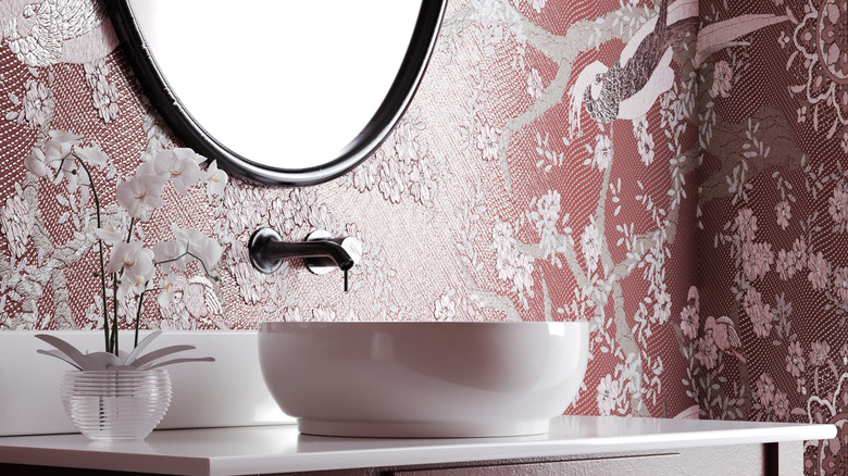 A bathroom vanity with textured vintage-style wallpaper.