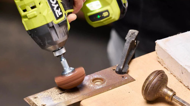 A person using the 5-piece Paint and Varnish Removal Set with a Ryobo drill