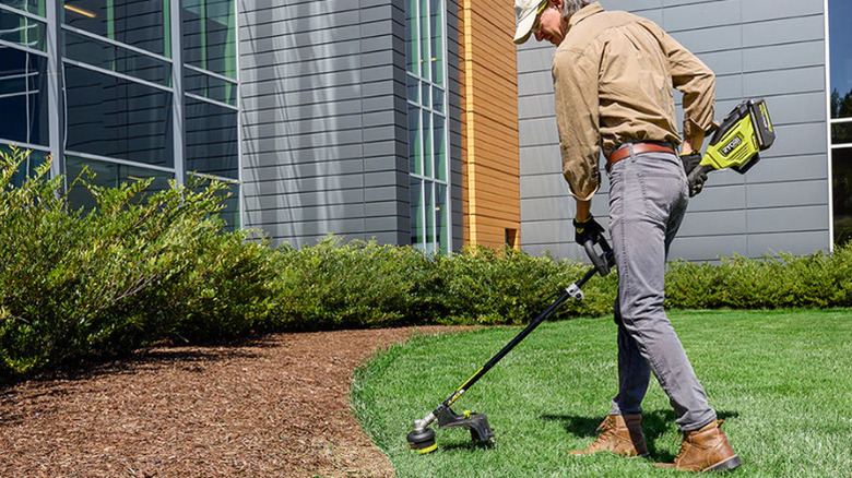 A person using Ryobi's 40V HP Brushless 17 inch Attachment Capable String Trimmer Kit