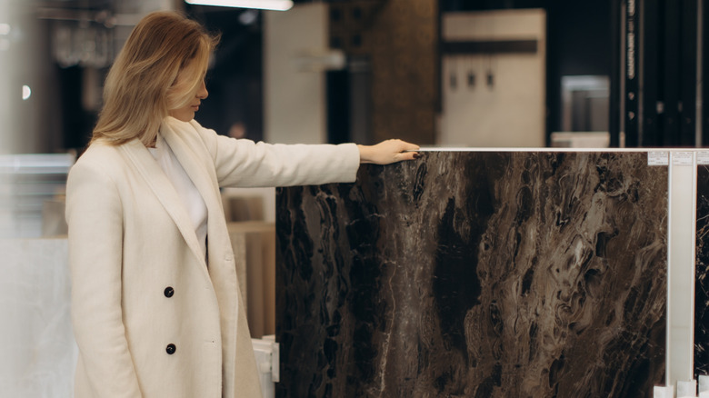 Woman Looking at dark marbled stone slab in store.