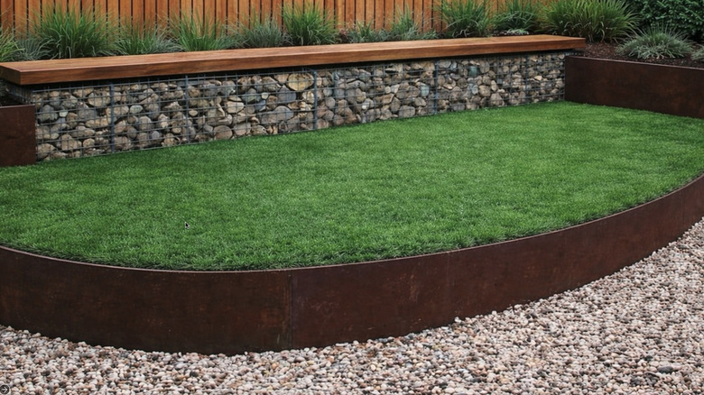 A rusted driveway edge with green grass