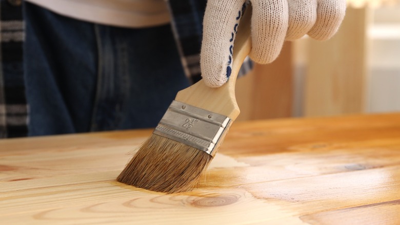 A person brushing stain onto a pine cabinet door