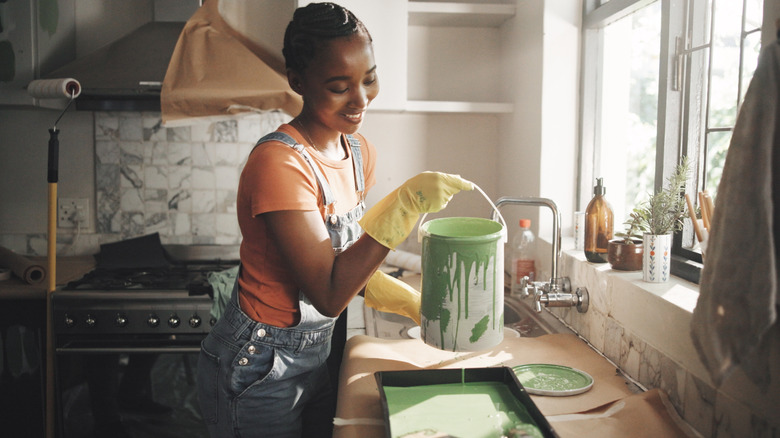 Woman pours green paint and prepares to paint her kitchen.