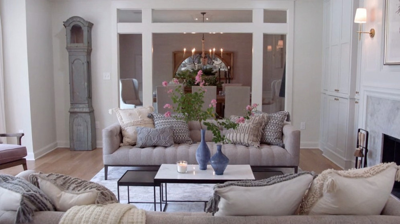 A living room with gray sofas and textured pillows with a grandfather clock in the corner.