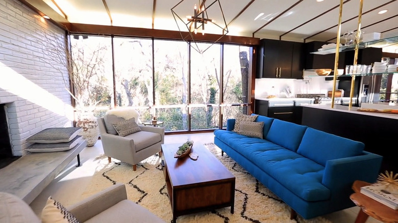 An open concept living space backing onto a kitchen with a bold blue couch facing a modern fireplace.