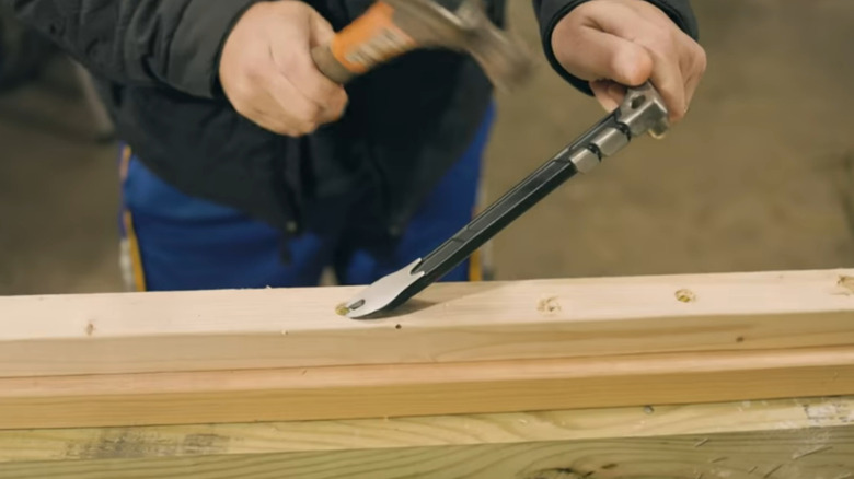 DeWalt 10 in. Claw Bar being used with a hammer to remove fasteners from wood